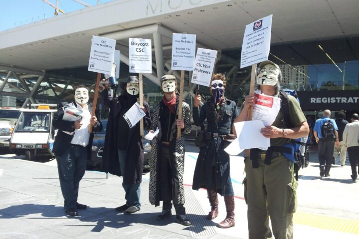 Occupy San Francisco protesters holding Boycott CSC War Profiteers signs outside Moscone Center